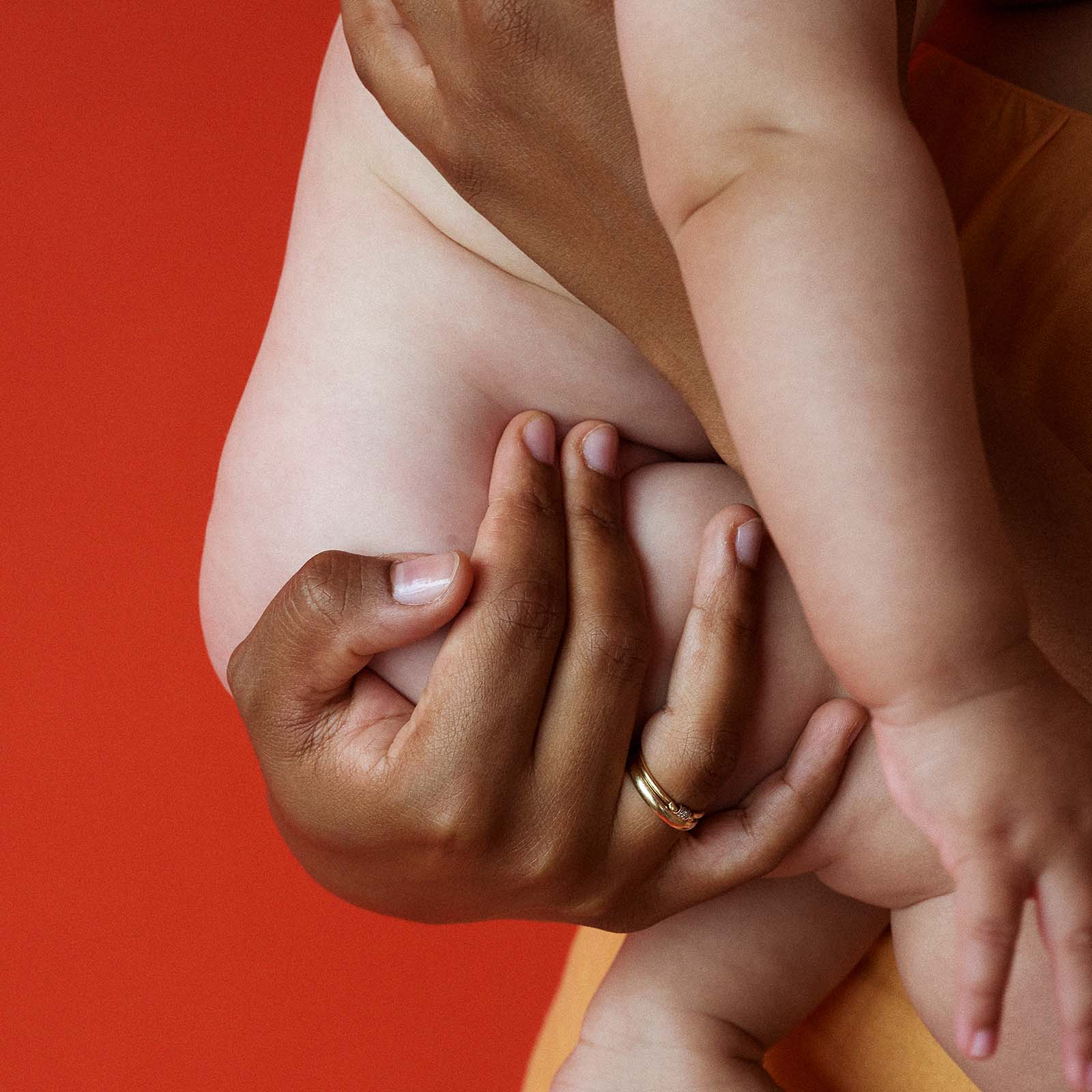 Detailaufnahme einer Mutter, die ihr nacktes Baby sanft am Körper hält – Symbol für hautfreundliche, natürliche SUMO Stoffwindeln ohne Chemikalien, die empfindliche Babyhaut schützen. Foto: Valeria Mitelman