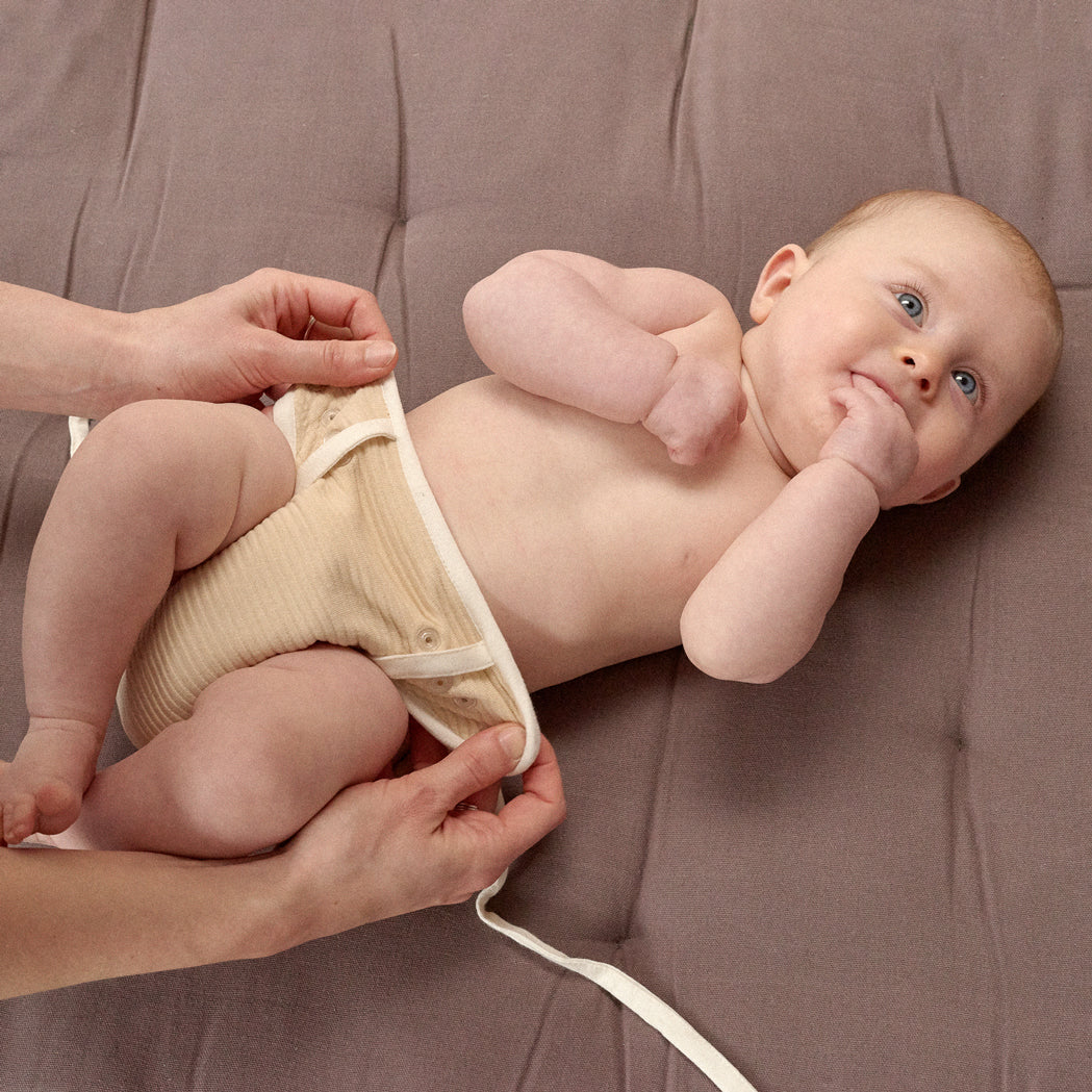 Baby in waschbarer Sumo Windel. Der Einfache Verschluss mit Druckknöpfen und Bändchen bietet passgenaues Einrichten der Windel 
